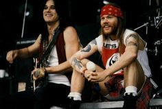 two men sitting on stage with one holding a ball and the other wearing a bandana