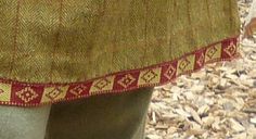 a close up of a person's leg wearing a dress with red and gold trim