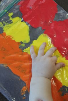 a child's hand touching the paint on a piece of paper