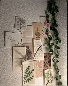 an arrangement of flowers and books on a wall with paper cut out to look like leaves