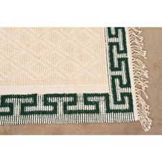 a green and white rug with fringes on the bottom is laying on top of a floor