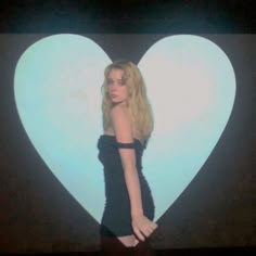 a woman is standing in front of a heart shaped wall with her hands on her hips