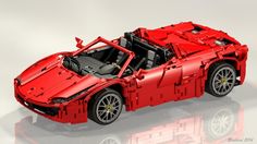 a red lego model of a sports car on a reflective surface with its hood up