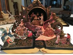 an open book with figurines on it sitting on a table next to other items