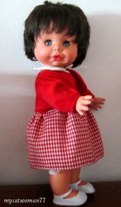 the doll is wearing a red and white dress