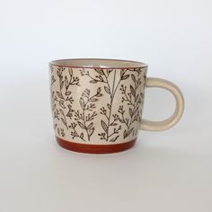 a coffee cup with brown and white designs on it's rim, sitting on a table