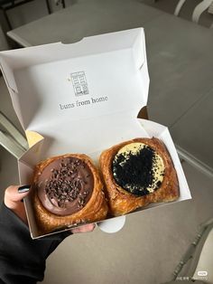 two pastries with chocolate frosting and sprinkles are in a box