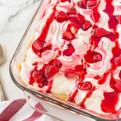 a dessert with strawberries and cream in a glass dish on a white tablecloth