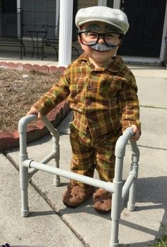 a little boy with a fake moustache on his face is standing next to a metal railing