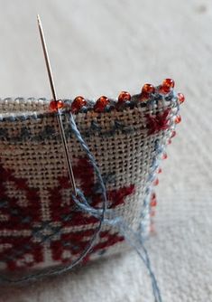 a close up of a needle in a basket with some thread on the table next to it