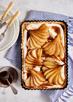 an apple tart sitting on top of a blue and white table cloth next to silverware