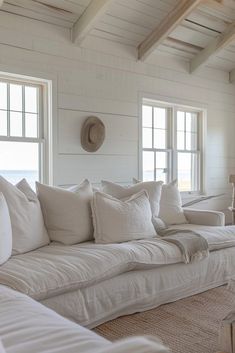 a living room filled with white furniture and lots of pillows on top of it's couches