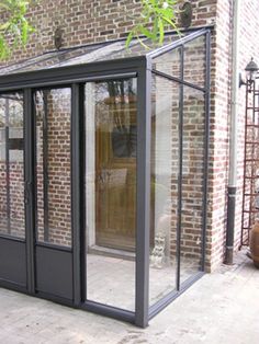 an outdoor room with glass doors on the outside and brick building in the back ground