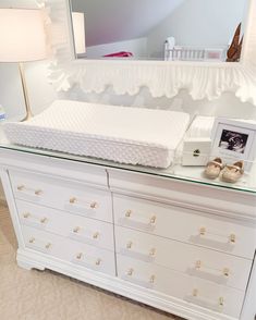 a white dresser with a baby's crib and shoes on it