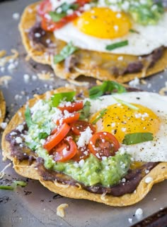 two tortillas topped with an egg and avocado on a baking sheet