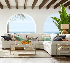 a living room filled with lots of furniture next to an ocean view window and wooden beams