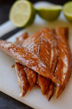 some kind of fish on a cutting board with limes and lemon wedges in the background