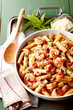 pasta with shrimp and parmesan cheese in a white bowl next to a wooden spoon