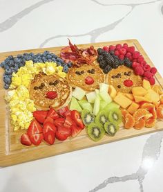 a wooden cutting board topped with fruit and pancakes