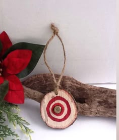 a wooden ornament with a red and white design on it next to a christmas tree branch