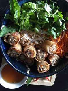 a blue bowl filled with food next to a cup of tea