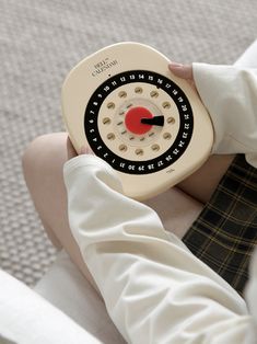 a person sitting on the floor holding a toy clock