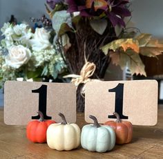 three small pumpkins sitting on top of a wooden table