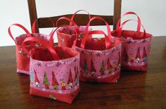 four small pink bags sitting on top of a wooden table next to a brown chair