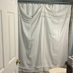 a white shower curtain in a bathroom next to a toilet