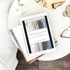 an ipad sitting on top of a white table next to a pair of glasses and books