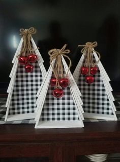 three wooden christmas trees with red ornaments on them, sitting on a black and white checkered tablecloth