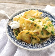 a blue and white plate topped with ravioli, sour cream and scallops