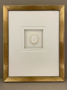 a white and gold framed photo with a medallion on it