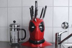 a red deadpool knife holder with knives sticking out of it's centerpiece