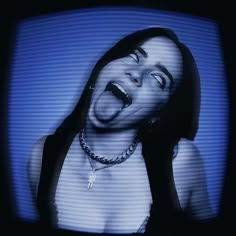 a woman with her mouth open and tongue out in front of a television screen that is turned on