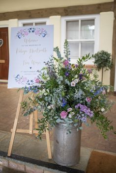 a metal bucket filled with flowers next to a sign