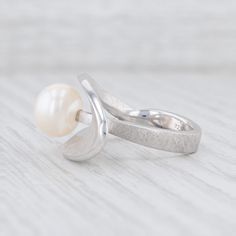 Bastian Inverun - Cleverly Positioned Pearl - 12876 / 26001 - Retail $465 Gem: Cultured Pearl -9.5 mm, Round Shape, White Color Metal: Sterling Silver Weight: 9.6 Grams (varies in weight per size) Stamps: 925 b. Face Height: 15.3 mm Rise Above Finger: 9.7 mm This ring is a size 56 / 7.5. Please check our store for more possible size options. Each piece is thoroughly examined and refinished as needed by our professional jewelers, graded by our in-house GIA (Gemological Institute of America) Gradu Timeless High Luster Rings For Formal Occasions, White Gold Rings With High Luster For Formal Events, White Gold Rings With High Luster For Formal Occasions, Elegant Concave Gemstone Rings, Modern White Gold Pearl Ring For Anniversary, Silver Ring With Timeless Design For Anniversary, Modern Pearl Open Ring For Anniversary, Modern Open Pearl Ring For Anniversary, Silver Rings With Timeless Design For Anniversary