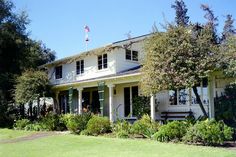 a large white house sitting on top of a lush green field