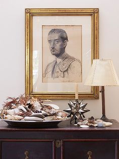 a table topped with a bowl of food next to a framed portrait on the wall