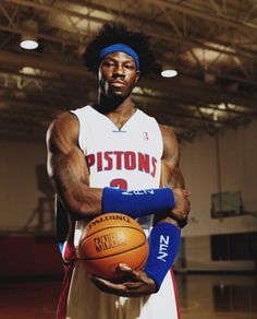 a man holding a basketball in his right hand and wearing a blue headband on the other