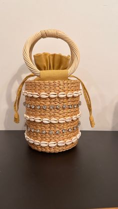 Our Leah Bag is our new favorite mini bag for spring and summer! With shell and stone embellished detail on a simple straw bag with round handles, this handheld adds style and personality to any outfit. Material: 100% Raffia, 100% Cotton Lining, Shell and Stone Detail Spot Clean with Damp Cloth Elegant Bucket Bag With Braided Handles For Beach, Elegant Beach Bag With Top Handle, Elegant Straw Bag With Handles For Beach, Elegant Beach Straw Bag With Handles, Chic Straw Bag With Round Handle For Beach, Chic Beach Straw Bag With Top Handle, Chic Top Handle Straw Bag For Beach, Elegant Straw Bag With Round Handle For Beach, Summer Beige Straw Bag With Pearl Handle