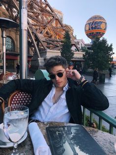 a man sitting at a table in front of the eiffel tower with a glass of water