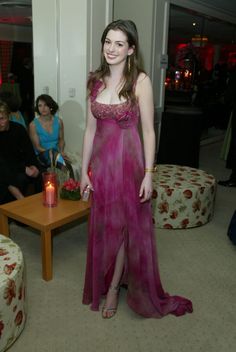 a woman in a long pink dress standing next to a table with candles on it