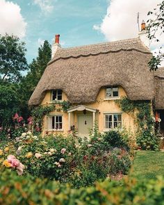 a thatched roof house with roses in the front yard