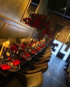 a long table is set up with candles and red roses in vases on it