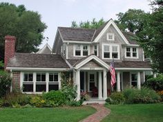 a large house with a flag on the front porch and two story windows in it