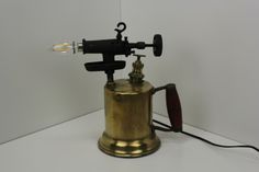 an old fashioned coffee grinder is sitting on a table next to a light bulb