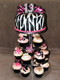 a tiered cake that has cupcakes on it with pink and black decorations