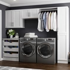 a washer and dryer in a room with clothes hanging on the rack above them