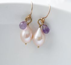 "Pich pearls accented by amethyst gemstone drops create these petite earrings. Wire wrapped securely, these plump Baroquo pearls have shimmering lustre. Dangling from 24 k vermeil French ear wire, they stay on securely and are just the right length to be noticeable.  Details: Baroque Pearl ( 10 x 15 mm.) Amethyst Measures: just over 1.4\" ( 35 mm.) Dangle earrings made of 24 k gold fill and French wire. * Processing time is 3 - 5 days.  * US orders are shipped first class mail. * International o Elegant Lavender Earrings With Ear Wire, Handmade Amethyst Earrings For Wedding, Handmade Amethyst Wedding Earrings, Elegant Purple Jewelry With Ear Wire, Elegant Purple Gemstone Pearl Earrings, Elegant Lavender Earrings With Gemstone Accents, Amethyst Earrings With Gemstone Accents For Wedding, Amethyst Gemstone Earrings For Wedding, Amethyst Gemstone Wedding Earrings